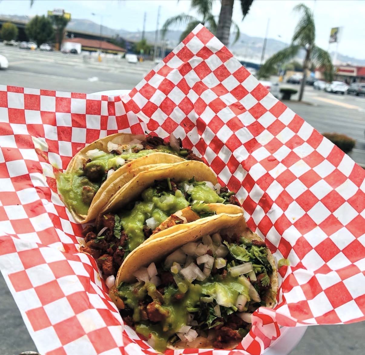 Three tacos with fresh salsa in a checkered basket